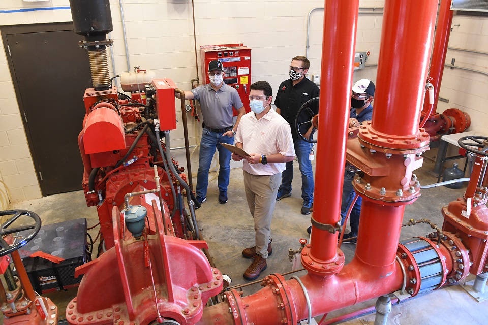 Pantex summer intern Drew Rowlands (center) checks a pump station system with coworkers Jonathan Burkhead (left), Ronnie Anderle (black shirt), and Colton Mooney (right).